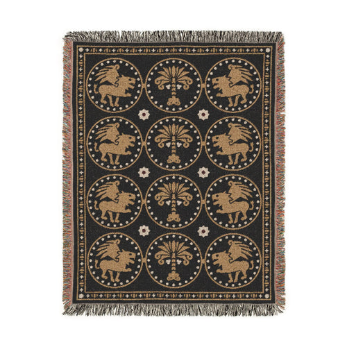 The Golden Bestiary woven throw, 54 × 70 in, winged lions and date palms in gold roundels on charcoal